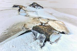 rocas rompiendo el hielo en eggum, islas lofoten, ártico, noruega, escandinavia, europa en un día nublado de invierno. foto