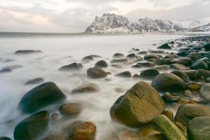 olas que fluyen sobre la playa de utakleiv, islas lofoten, noruega en el invierno. foto