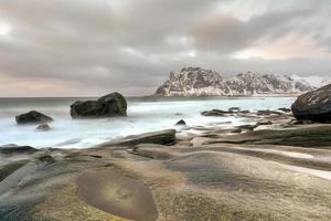 olas que fluyen sobre la playa de utakleiv, islas lofoten, noruega en el invierno. foto