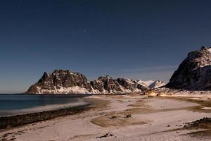 Playa utakleiv iluminada por la luna, islas lofoten, noruega en invierno. foto