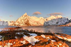 cabaña de pesca en el pico de la montaña hamnoy y lilandstinden en invierno en reine, islas lofoten, noruega. foto