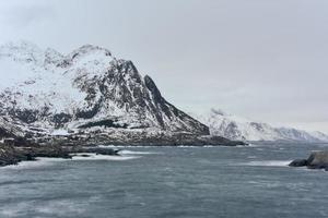 cabaña de pesca en el pico de la montaña hamnoy y lilandstinden en invierno en reine, islas lofoten, noruega. foto