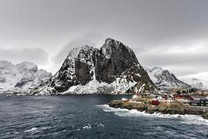 cabaña de pesca en el pico de la montaña hamnoy y lilandstinden en invierno en reine, islas lofoten, noruega. foto