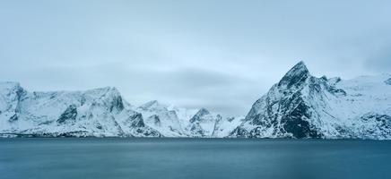 cabaña de pesca en el pico de la montaña hamnoy y lilandstinden en invierno en reine, islas lofoten, noruega. foto