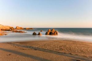 Stunning long-exposure view of smooth waves crashing into rock formations at sunset, Sequit Point, Leo Carrillo State Beach, Malibu, California photo