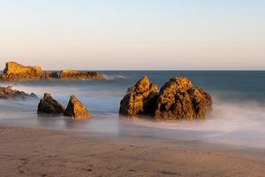 Stunning long-exposure view of smooth waves crashing into rock formations at sunset, Sequit Point, Leo Carrillo State Beach, Malibu, California photo