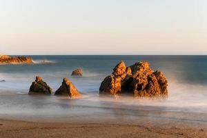 Stunning long-exposure view of smooth waves crashing into rock formations at sunset, Sequit Point, Leo Carrillo State Beach, Malibu, California photo
