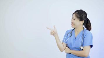asiatisk kvinna läkare pekande en tecken på en vit vägg. video