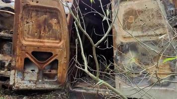 vista de autos quemados después de ataques con cohetes. guerra de rusia contra ucrania. vehículo civil después del incendio. cementerio de autos en la ciudad de irpin. montón de metal oxidado. piezas de hierro de un coche quemado video