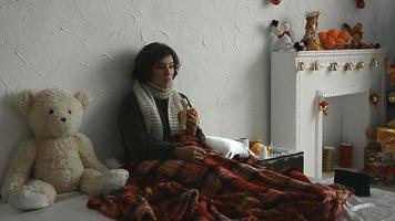 Sick girl in the sweater lies in bed and eats a banana at home video