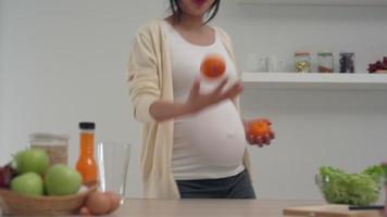 mulher grávida tem laranja nas mãos na cozinha durante a preparação do suco de laranja. boa emoção na mulher grávida ajuda o feto para o desenvolvimento do cérebro. o conceito de emoção afeta o desenvolvimento. video
