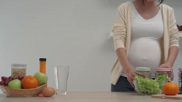 Eine glückliche schwangere Frau handhabt glücklich Flaschen in der Küche. die Frau erledigt die Hausarbeit, um sich zu entspannen und gute Laune zu haben. video
