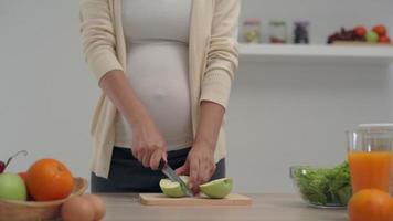 une femme enceinte cueillait une pomme verte et utilisait un couteau pour couper la pomme et faire du jus de pomme. la pomme verte aide les mères à se sentir fraîches et fournit des vitamines à l'enfant à naître. video