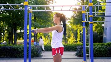 beautiful caucasian brunette woman train her hands with dumbbells at warm sunny day at the park video