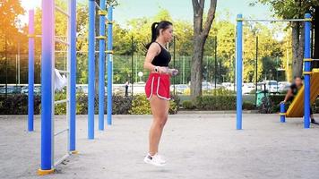 femme brune adulte faisant des squats à la salle de sport de rue à l'extérieur lors d'une chaude journée d'été video