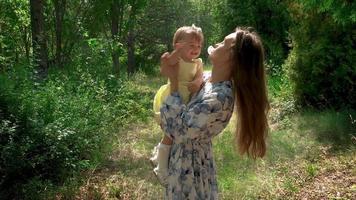 schattig jong moeder met beetje baby meisje in bloemen Bij de park buitenshuis video
