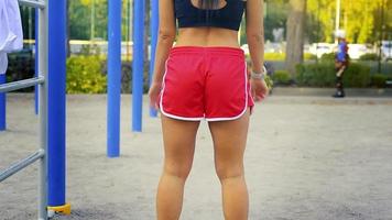 young adult brunette woman doing a squats at the street gym outdoors at warm summer day video