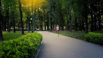hübsche kaukasische brünette läuferfrau, die im park übt, während sie mus hört video