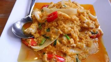 Thais voedsel roergebakken krab vlees met kerrie poeder geel oranje met lepel geplaatst Aan een wit bord. video