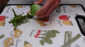 Chef's hand slices green eggplant with a sharp knife on a cutting board. video