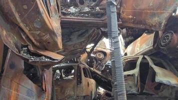 View of burned-out cars after rocket attacks. War of Russia against Ukraine. Civil vehicle after the fire. Cemetery of cars in the city of Irpin. Rusty pile of metal. Iron parts of a burnt car