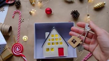 Key to house with keychain on cozy home in gift box with Christmas decor packaging. Pack present for New Year, Christmas. Building, project, moving to new house, mortgage, rent, purchase real estate
