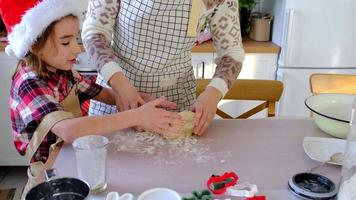 mãe e filha na cozinha branca estão preparando biscoitos para o natal e ano novo. dia da família, preparação para o feriado, aprenda a cozinhar deliciosos pastéis, corte formas de massa com moldes video