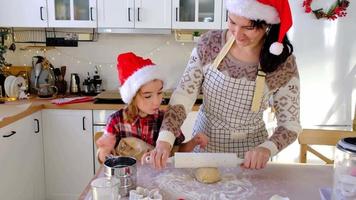 Mom and daughter in the white kitchen are preparing cookies for Christmas and new year. Family day, preparation for the holiday, learn to cook delicious pastries, cut shapes out of dough with molds video