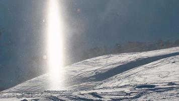 snowboarder passa feixe de partículas de neve ensolarada em clima de dia ensolarado ao ar livre. fundo de banner de partículas afeta video