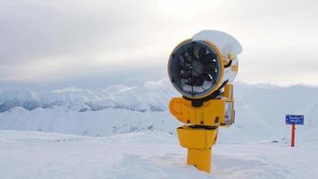 Yellow snow cannon under snow in Gudauri ski resort in snowy mountains after fresh snow fall. Good snow situation and fake snow technology video