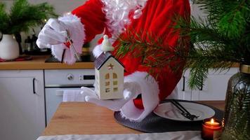 chiave di casa con portachiavi cottage nelle mani di babbo natale all'aperto nella neve. affare per immobili, acquisto, costruzione, trasloco, mutuo. casa accogliente. buon natale, evento di prenotazione di capodanno e sala video