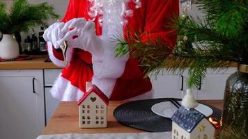 Hausschlüssel mit Schlüsselanhänger Häuschen in den Händen des Weihnachtsmanns im Freien im Schnee. Deal für Immobilien, Kauf, Bau, Umzug, Hypothek. gemütliches zu Hause. frohe weihnachten, neujahrsbuchungsveranstaltung und halle video