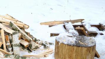 A man is chopping firewood with an axe in winter in the snow. Alternative heating, wood harvesting, energy crisis video