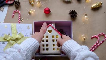 Key to house with keychain on cozy home in gift box with Christmas decor packaging. Pack present for New Year, Christmas. Building, project, moving to new house, mortgage, rent, purchase real estate video