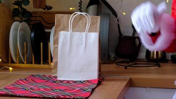 le père noël le met sur la table de la cuisine et emporte des sacs en papier avec des cadeaux artisanaux, des gâteaux faits maison et la livraison de nourriture. éco-responsable, recyclage des emballages, fait main, livraison pour noël et nouvel an video