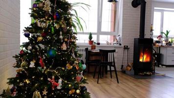 l'intérieur festif de la maison est décoré pour noël et le nouvel an dans un style loft avec poêle noir, cheminée, arbre de noël. chambre studio chaleureuse avec table dressée, feu de bois, cosy et chauffage d'accueil video