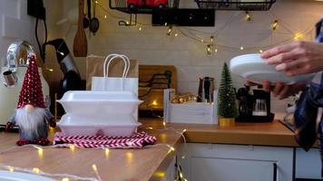 Woman puts it on table and takes food delivery service containers on table white scandi festive kitchen in christmas decor. Eve New year, saving time, too lazy to cook, hot order, plastic box video