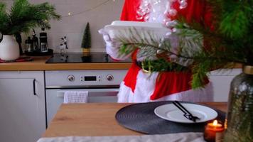 cibo consegna per casa servizio contenitori nel mani di Santa Claus mette esso su cucina tavolo e prende esso lontano. già pronto caldo ordine, Natale, nuovo anno vacanze ristorazione. video