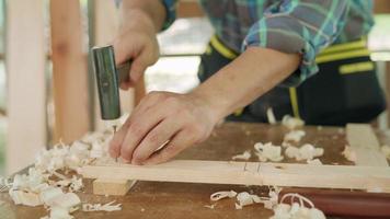 asiatischer mann, besitzer ein kleines holzgeschäft bereitet holz für die möbelproduktion vor. Zimmermann passt die Oberfläche des Holzes auf die gewünschte Größe an. Tischlerkonzept und Kleinunternehmer. video