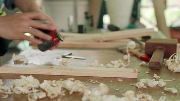 el dueño de un hombre asiático, un pequeño negocio maderero, está preparando madera para la producción de muebles. el carpintero está ajustando la superficie de la madera al tamaño deseado. concepto de carpintero y propietarios de pequeñas empresas. video