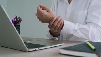 business man squeezing his wrist to relieve pain in his arm. Businesswoman has a pain in her wrist from using the computer for a long time. Concept Office syndrome video