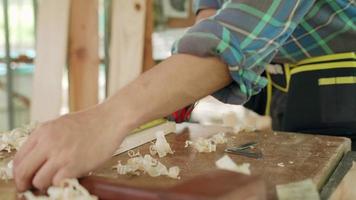 el dueño de un hombre asiático, un pequeño negocio maderero, está preparando madera para la producción de muebles. el carpintero está ajustando la superficie de la madera al tamaño deseado. concepto de carpintero y propietarios de pequeñas empresas. video