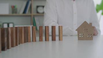 Versicherung mit Händen schützen Domino. geschäftsmannhände stoppen dominosteine, die in geschäftskrisen fallen. Kontrolle und Planung von Geschäftsrisiken sowie Strategien zur Führung von Versicherungsgeschäften. video