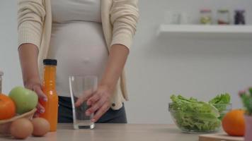 zwanger vrouw drinken een oranje sap. kiest een voedzaam voor de gezond ontwikkeling en groei van haar ongeboren kind. vitamine Aan fruit belangrijk voor zwanger vrouw. video