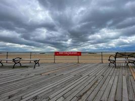 señal de distanciamiento social en un parque de la ciudad de nueva york en el paseo marítimo a lo largo de la playa de brighton durante la epidemia de coronavirus. foto