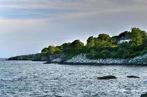 The cliffwalk in Newport offers backyard views of famous mansions to one side and a beautiful rocky coastline to the other in Newport, Rhode Island, USA. photo