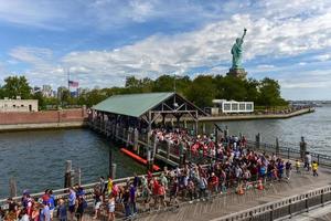 New York City - September 11, 2016 -  The Statue of Liberty from Liberty Harbor with a crowd of tourists awaiting to take a boat to Ellis Island. photo