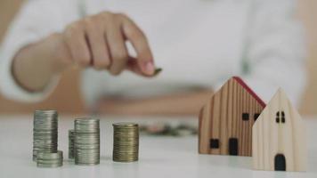 Frauen behalten Geld, um für die Zukunft zu investieren. die leute legen münzen für den kauf nach hause. Sparen Sie Geld für Investition und Hauskonzept und reservieren Sie. video