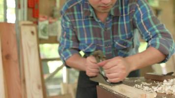 Asian man owner a small lumber business is preparing wood for furniture production. carpenter is adjusting the surface of the wood to the desired size. Carpenter concept and small business owners. video