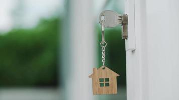 Landlord house key for unlocking a house is plugged into the door. Second hand house for rent and sale. keychain is blowing in the wind. Landlord for new house, rent , sale, renovate, investment. video